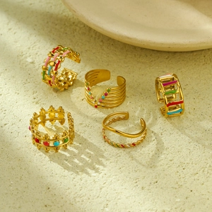 Flat lay of five 18K gold plated stainless steel rings with colorful enamel details