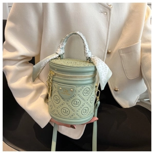 Detail of light green cylindrical handbag with silk scarf handle and gold hardware