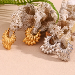 Detailed view of gold and silver pleated hoop earrings on natural coral and seashells
