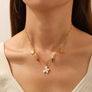 Gold stainless steel necklace featuring star, butterfly and gemstone pendants on model