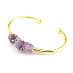 Detail view of handmade gold open bangle with raw purple amethyst crystals and wire wrapping