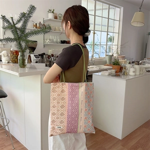 Détail du sac cabas en toile à fleurs colorées avec étiquette Sezakka et texture en tissu