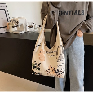 Detail of canvas tote bag featuring cartoon animal prints and black handle on female model