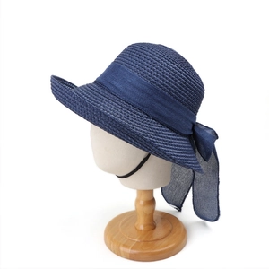 Detail of navy blue straw sun hat with large bow and breathable woven texture on stand