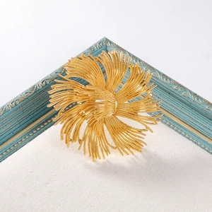 Detail of a vintage golden swirl brooch displayed inside an artistic retro frame