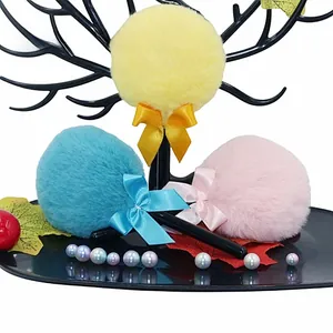 Detail of plush makeup powder puff with soft ribbons in yellow, blue and pink colors