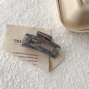 Detail of grey-blue marble patterned acetate hair claw clip on beige fabric