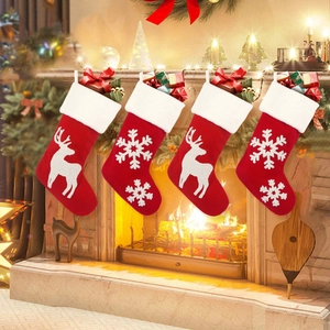 Set of 4 red knitted Christmas stockings with reindeer and snowflake on fireplace
