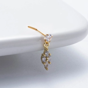 Gros plan d'un piercing de nez en L doré avec pendentif en zircon sur céramique blanche
