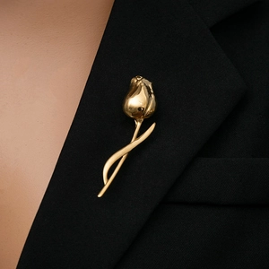 Detailed view of an elegant golden tulip brooch pinned on a black suit lapel