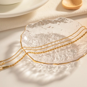 Elegant gold titanium steel chain bracelet set featuring snake and bead styles on a glass dish