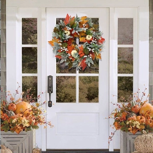 Detail of autumn wreath with pumpkins and maple leaves hanging on a white front door