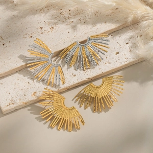 Detailed view of textured fan-shaped earrings in gold and silver finish on stone