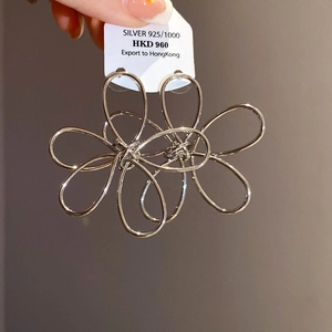 Macro shot of silver hollow flower pendant earrings with intricate 925 silver metal wire details