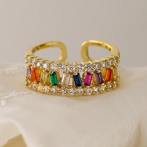 Adjustable gold plated open ring with colorful rainbow zircons on white lace background