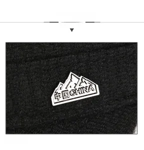 Detail view of black knit fabric with a silver mountain emblem and China engraving