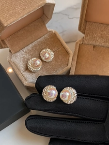 Dettaglio macro di orecchini di perle in argento martellato su un vassoio per gioielli beige