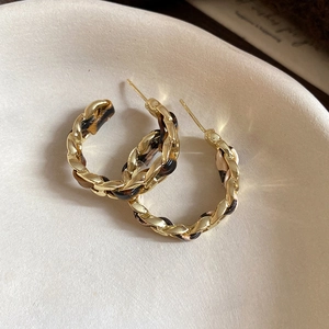 Detail of leopard print fabric woven through golden metal chain C-shaped hoop earrings