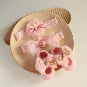 Detailed view of pink baby lace headband and bow socks set on a textured ceramic tray