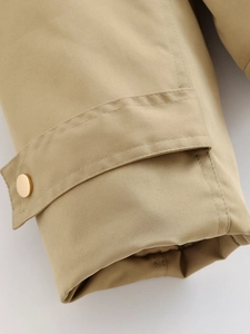 Detail of khaki twill fabric cuff with a decorative gold metal button and fine stitching