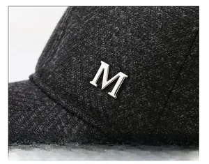 Makrodetail aus dunkelgrauem Twill-Stoff und silbernem M-Emblem auf der Winter-Baseballkappe