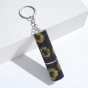 Sparkly rhinestone-studded perfume bottle keychain with black and yellow crystal pattern