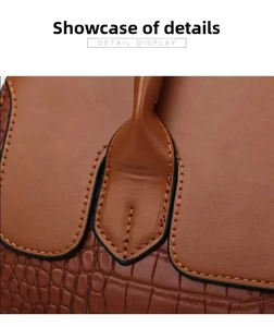 Detail view of crocodile-patterned brown leather handbag with reinforced stitching