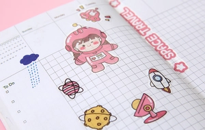 Close-up of cute cartoon space travel PVC stickers on a grid planner page