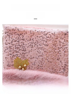 Detail von rosa Pailletten und Plüsch-Fell mit goldenem Stechpalmenblatt auf Socke