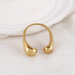 Macro detail of a minimalist gold open ring with teardrop ends on white textured fabric