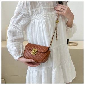 Close-up of brown quilted leather crossbody bag with gold lock and chain strap