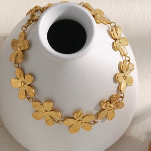 18K gold plated daisy flower link bracelet with brushed metal finish on ceramic vase