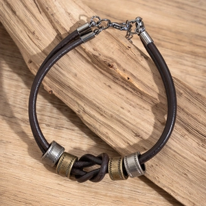 Dettaglio di un bracciale da uomo in pelle retrò con perle di metallo e chiusura a moschettone