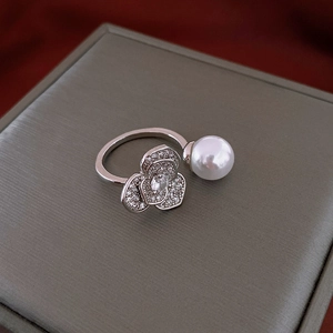 Detail of gold-plated tiger eye ring featuring intricate floral patterns and pearl accent