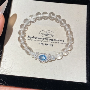 Detail of crystal bead bracelet with blue gemstone and silver lace setting on retro card