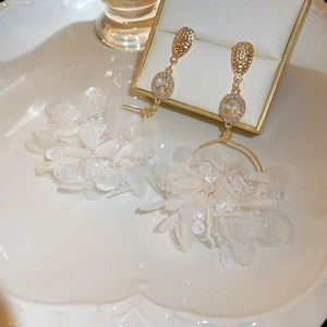 Detail of white translucent mesh flower petals and crystals on elegant gold drop earrings