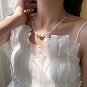 Detail of layered silver necklace with three brushed beads worn on a model's collarbone