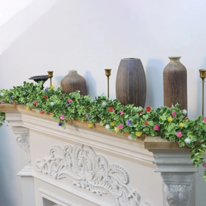 Detailed eucalyptus garland with colorful flowers draped over a white fireplace mantel