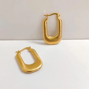 Detail of gold U-shaped tassel earrings with vertical striped texture and lever-back clasp