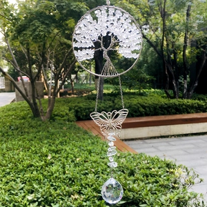 Handmade silver Tree of Life suncatcher with crystal ball and butterfly hanging in a garden