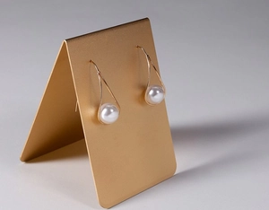 Detail of drop pearl earrings on a gold metal stand with high-quality polished finish