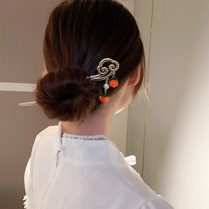 Gros plan d'un pic à cheveux doré de style chinois avec pampilles kaki et perles