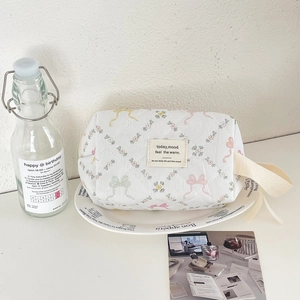 Détail d'une trousse à maquillage matelassée à fleurs avec poignée en ruban crème