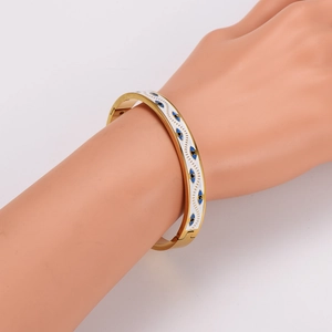 Gold stainless steel evil eye bangle with white enamel and blue eye details