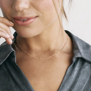 Detailed view of an 18k gold-plated snake bone chain necklace with satellite gold beads