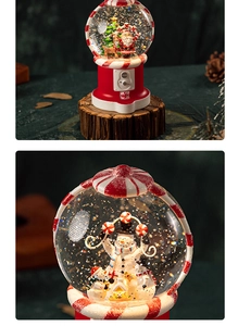 Macro shot of snowman and Santa scenery inside a red candy machine snow globe