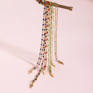 Gold plated stainless steel cross necklace with colorful enamel beads on a pink background