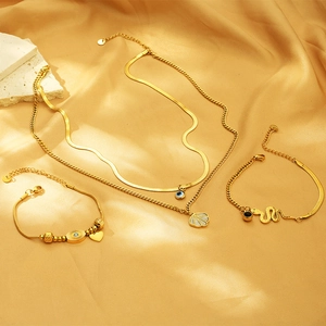 Detail of gold double necklace with evil eye and heart charms on silk background