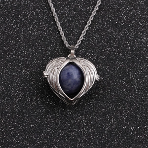 Detailed view of silver heart angel wing necklace with a round blue gemstone on black background