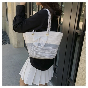 Detailed close-up of woven tote bag with a white bow and two-tone color stitching